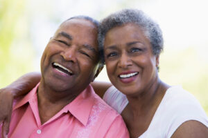 An older adult couple laugh and smile as they hug.