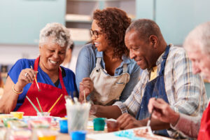 A group of older adults attend an art class with an instructor.